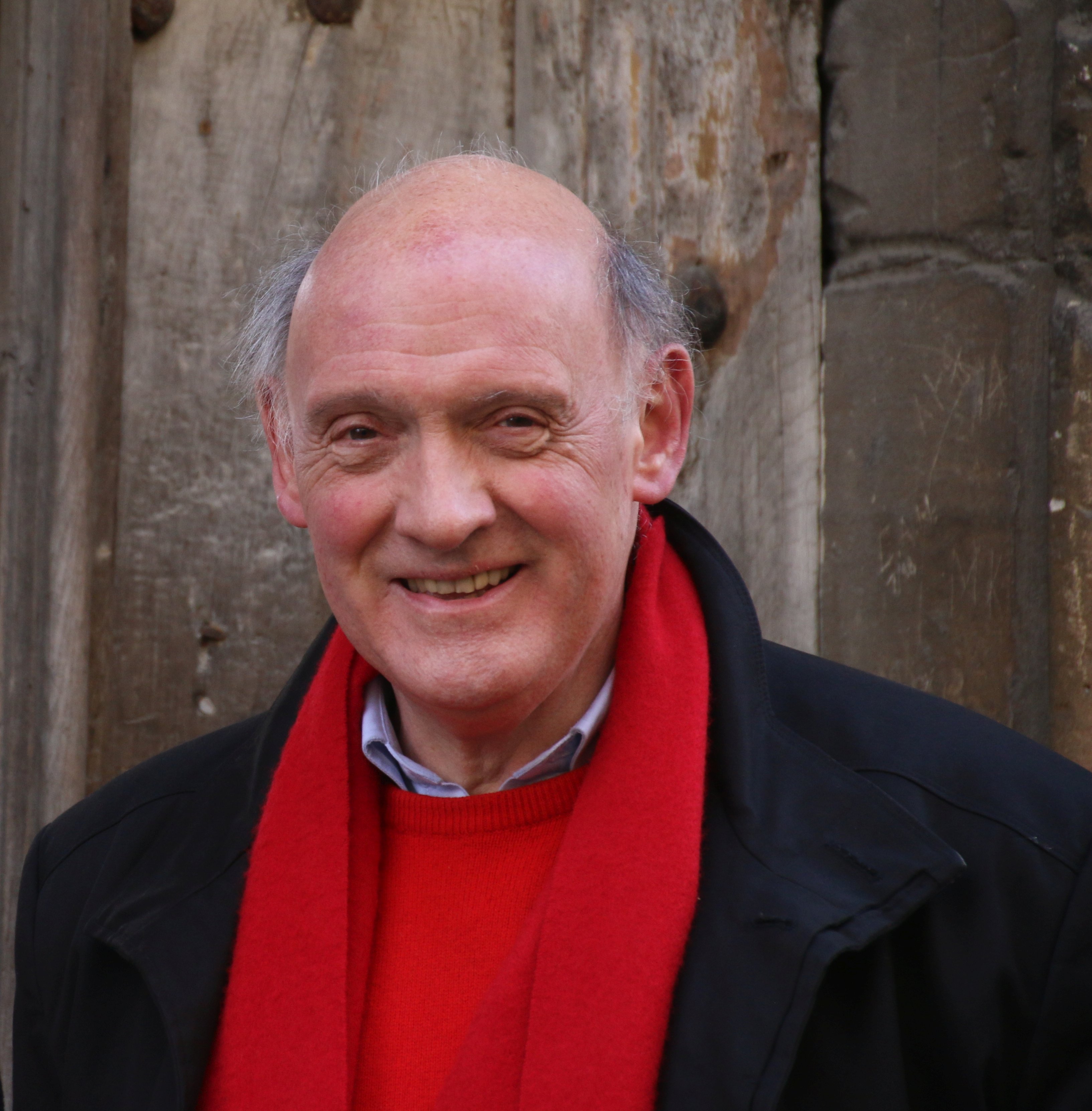 A profile photo of Professor Richard Carwardine CMG. He is wearing a red jumper and a red scarf.