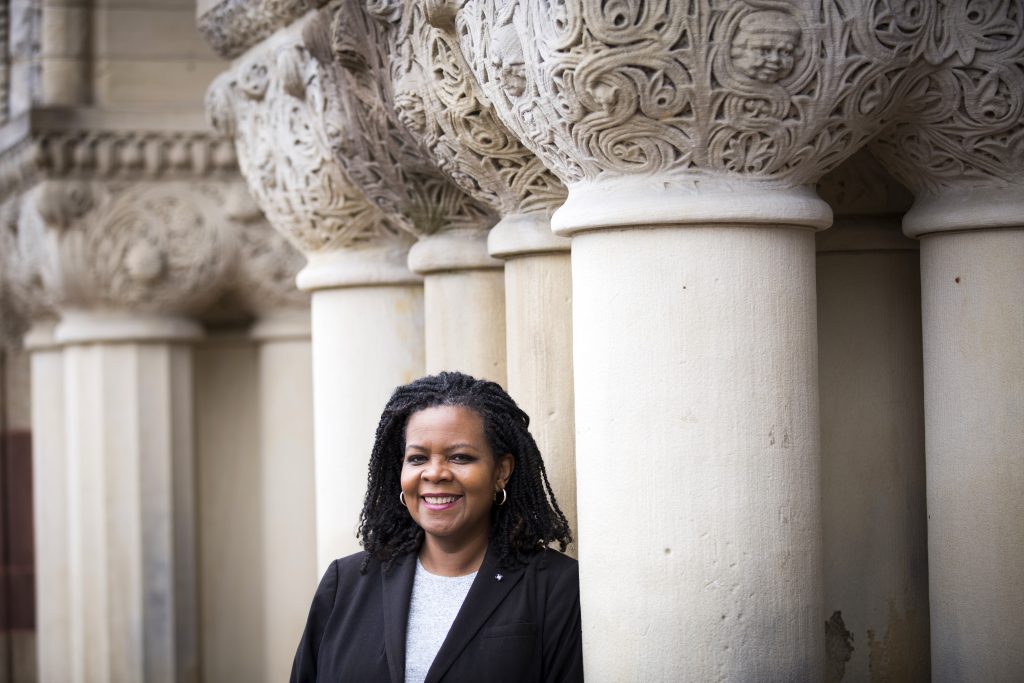 Profile photo of Prof Annette Gordon-Reed. She wears a dark suit and white t-shirt and stands in front of ornate stone columns.