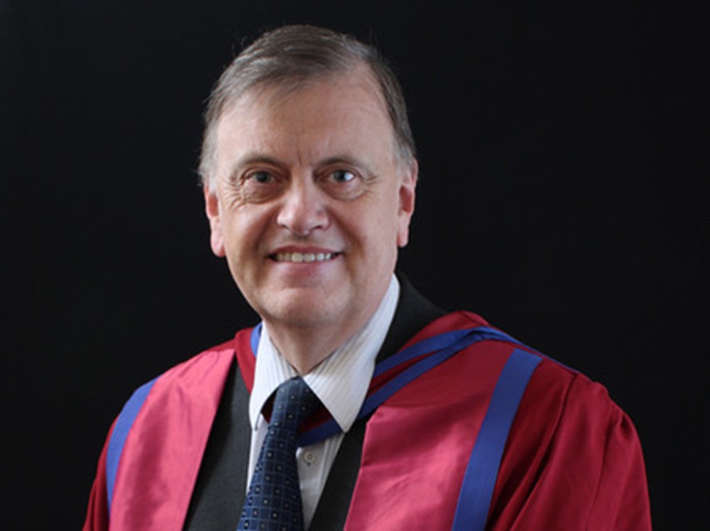 Prof John Sloboda's profile photo. He is wearing a suit and tie with an academic gown which is red.