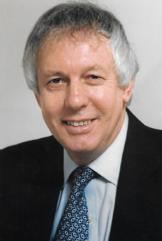 Profile photo for Sir Paul Lever. Sir Paul wears a dark suit with a blue tie.