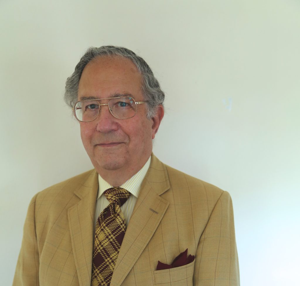 Profile photo of Peter Hacker. He wears a tan suit with a checkered tie.