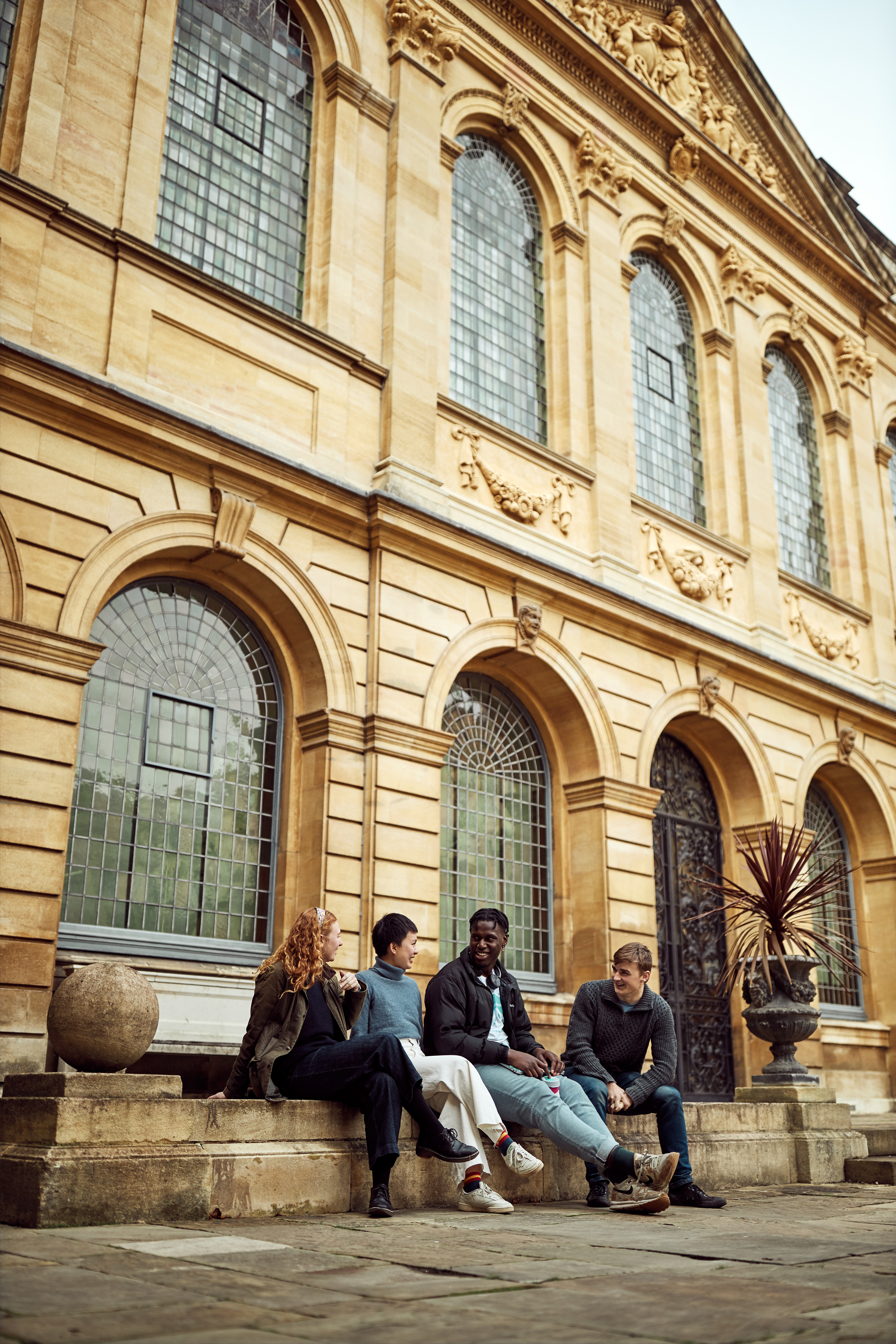 students sitting on the steps underneath the library building in Back Quad