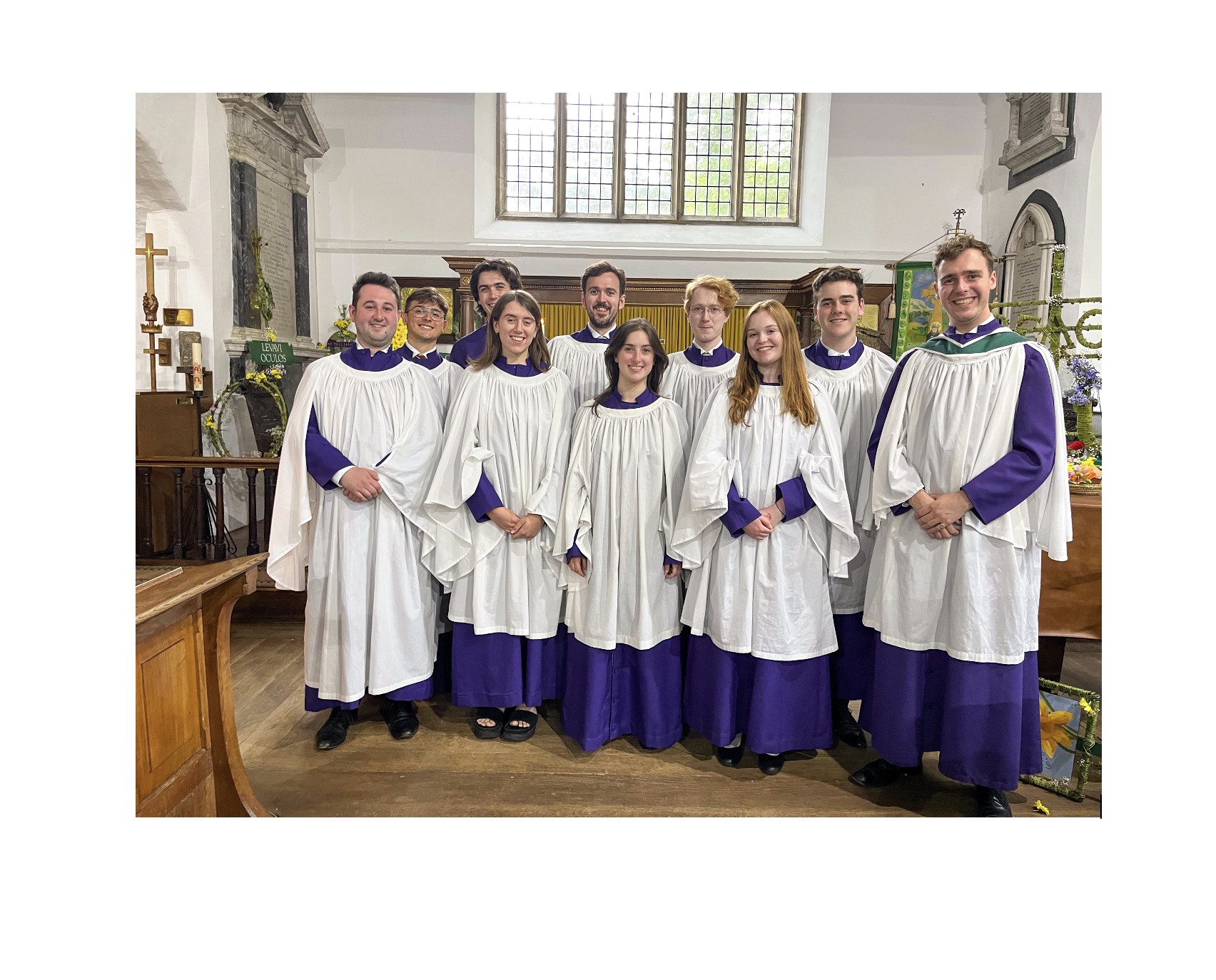 A group of singers from the choir dressed in their robes (white over purple)
