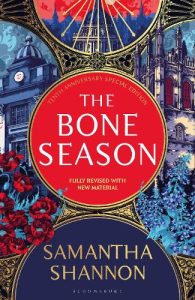 The Bone Season book cover with the title in a red circle in the centre and Oxford buildings and dark floral arrangements around the edges