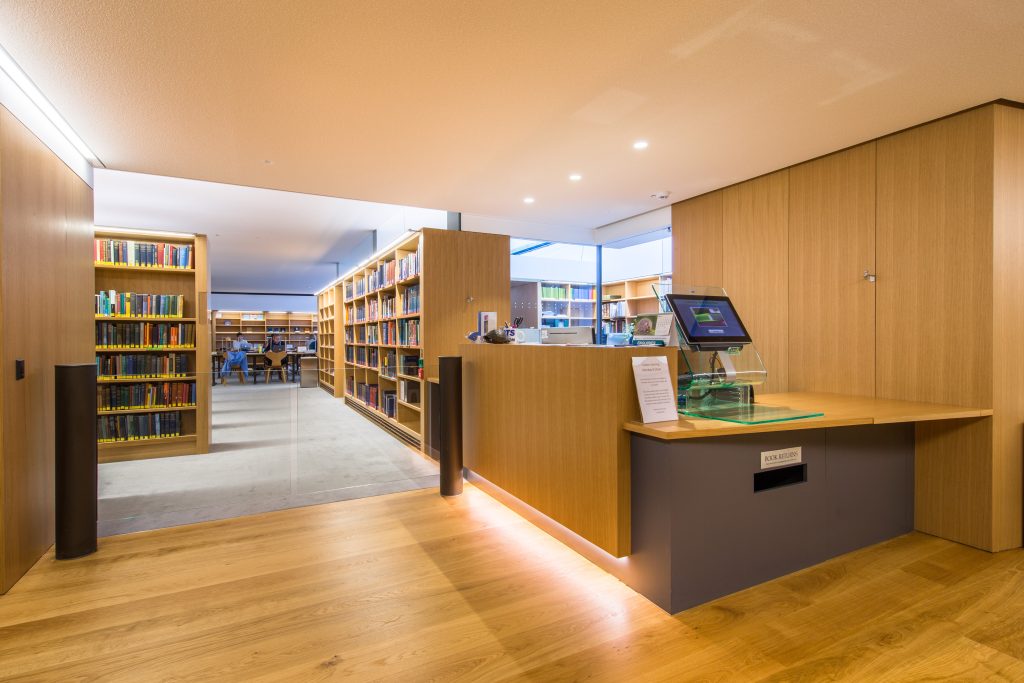 the welcome desk area of the basement library showing a wooden floor and bookshelves in the background