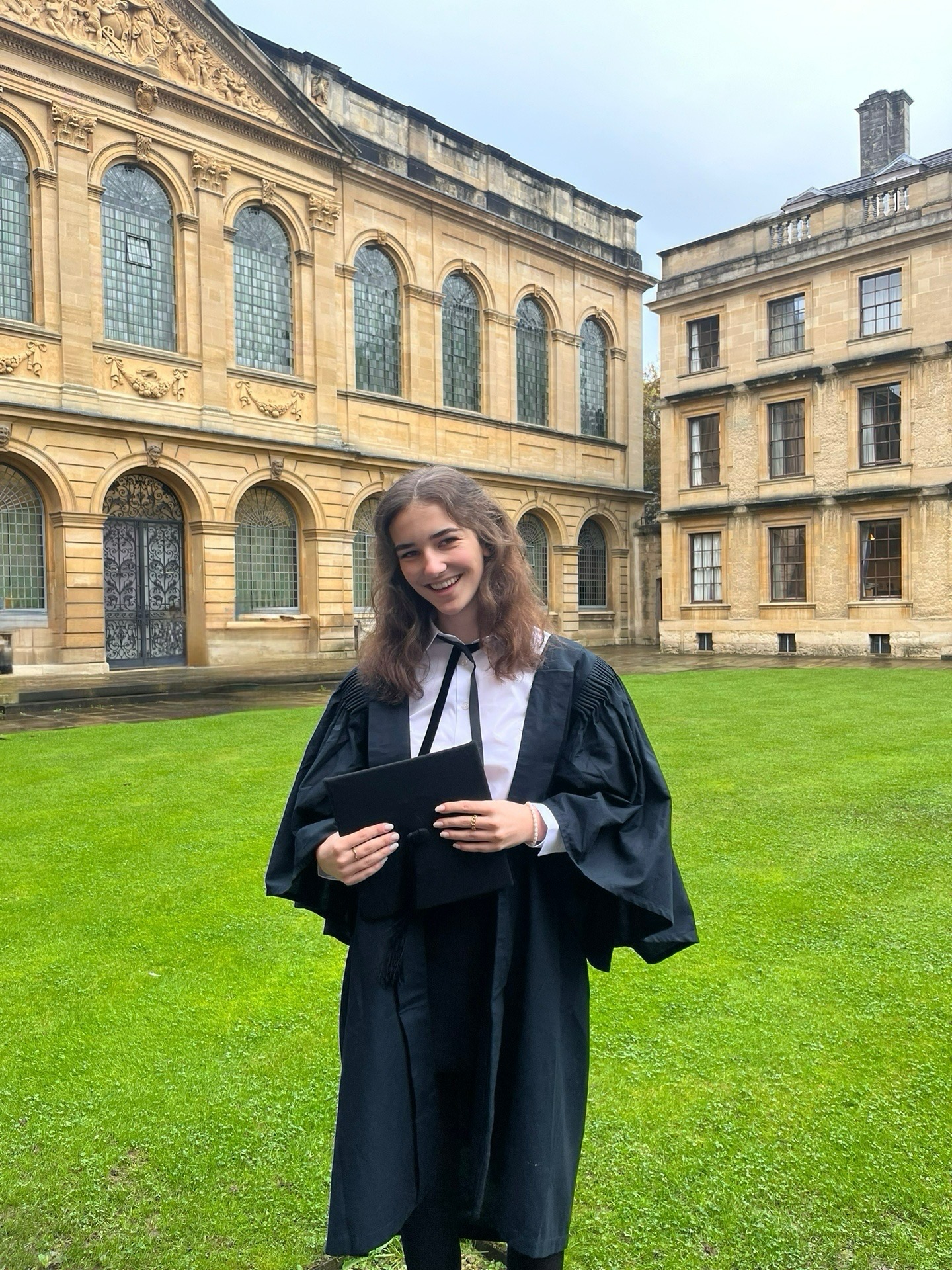 Hannah wearing subfusc standing in Back Quad in front of the Library