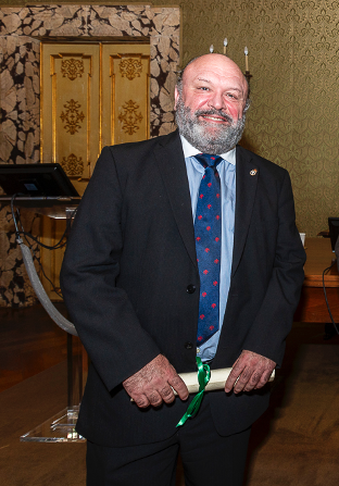 Prof Jose Carrillo pictured at the awards ceremony collecting holding a scroll tied with a green ribbon