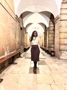 Cheryl's profile photo: she stands in the cloister at Queen's and smiles at the camera