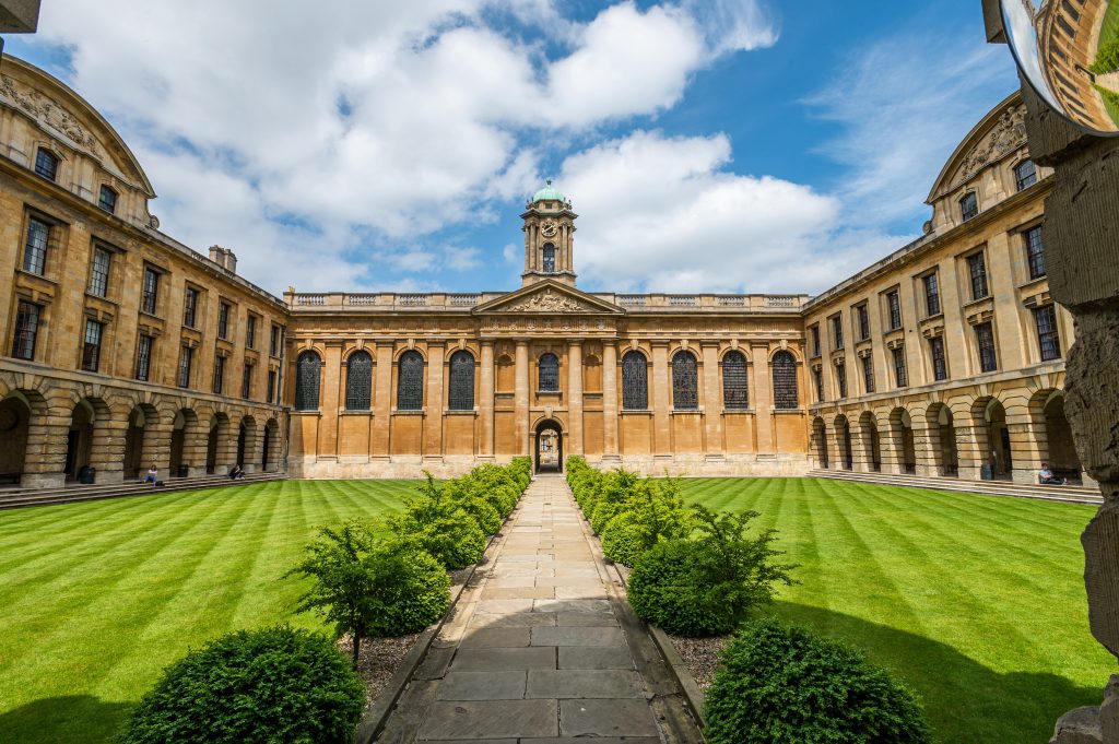 Front Quad wide angle shot showing the clock tower, green lawns, box hedge and a blue sky