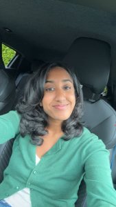 Nikita's profile photo. She is sitting in a car wearing a green cardigan.