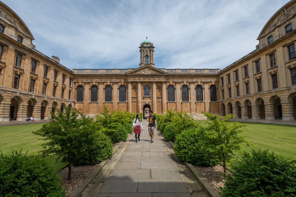 The Front Quad of Queen's showing two students walking towards the camera down the central path chatting