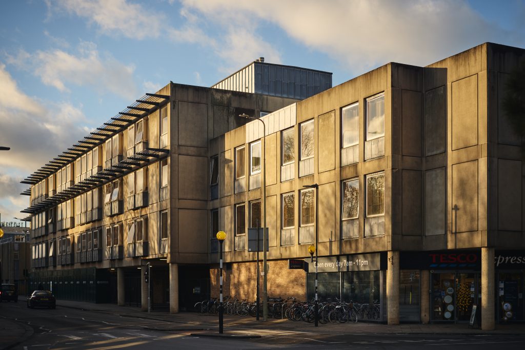 St Aldate's House exterior: a modern concrete building with large windows at the corner of two streets and above a Tesco metro