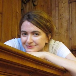 profile photo of Audrey Borowski leaning on her arms on a wooden shelf and looking at the camera