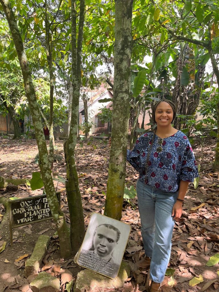 Tori Harwell standing with 146-year-old cocoa tree planted by Tetteh Quarshie.