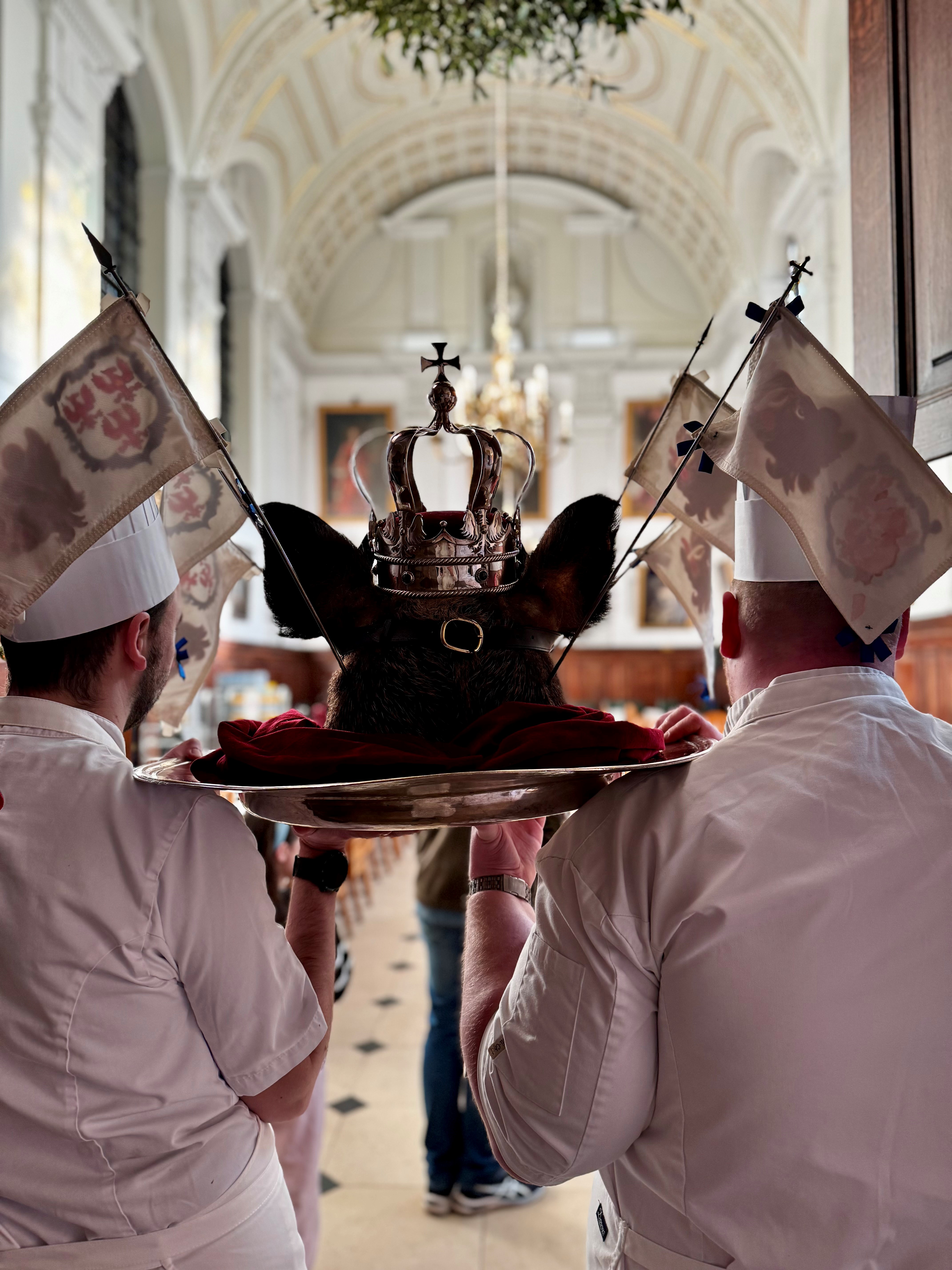 A photo from behind two chefs carrying a tray with the Boar's Head on into the Dining Hall. 1st Place winner in the Queen's Now category, Title: Behind The Boars Head Sean Ducie