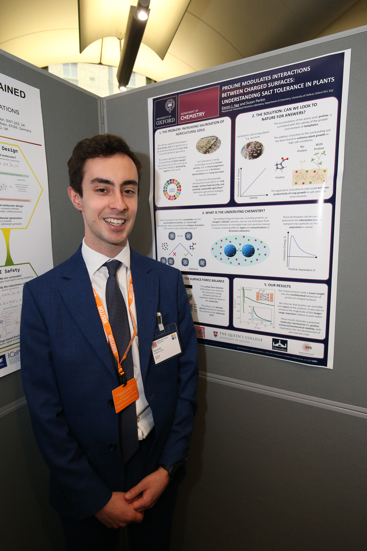 Kieran Agg standing next to his science poster entitled “Proline modulates interactions between charged surfaces: understanding salt tolerance in plants”.